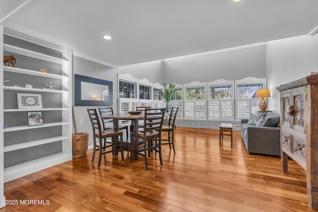 dining space with hardwood / wood-style floors, crown molding, and built in features