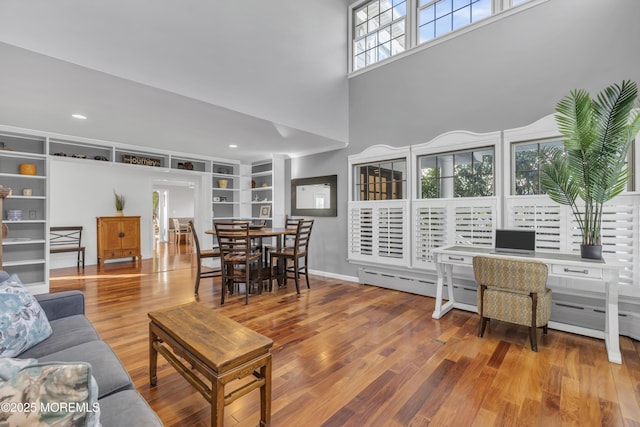 living room featuring a high ceiling, hardwood / wood-style floors, and built in features