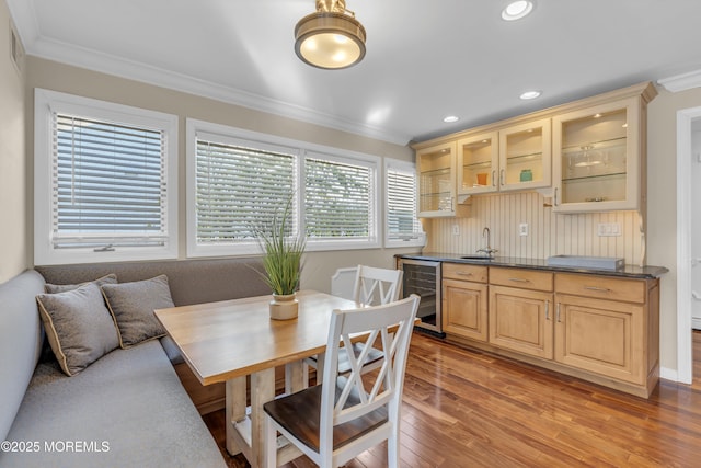 dining area with sink, beverage cooler, light hardwood / wood-style floors, and crown molding