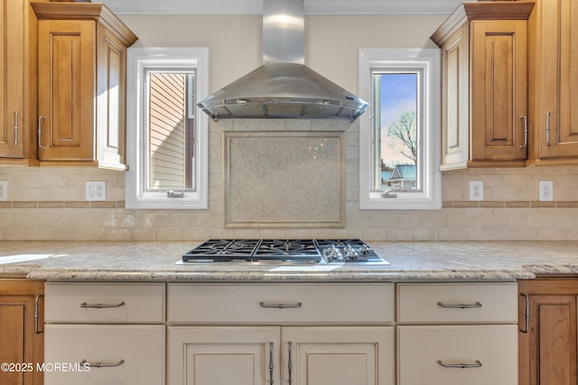 kitchen with light stone countertops, stainless steel gas stovetop, island exhaust hood, and tasteful backsplash