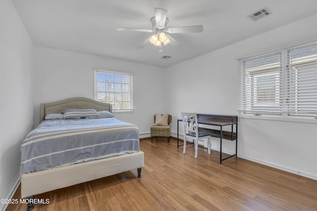 bedroom featuring light wood-type flooring, ceiling fan, and a baseboard radiator