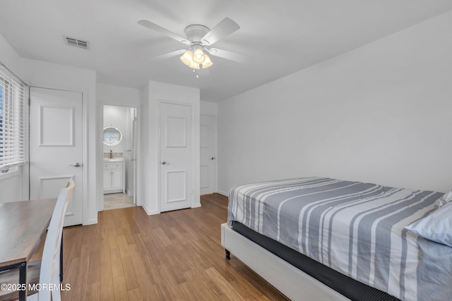 bedroom featuring sink, ensuite bath, ceiling fan, and light wood-type flooring