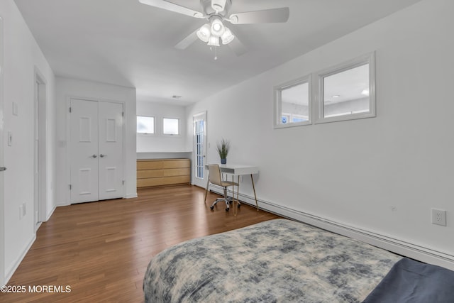 bedroom featuring wood-type flooring, a closet, ceiling fan, and baseboard heating