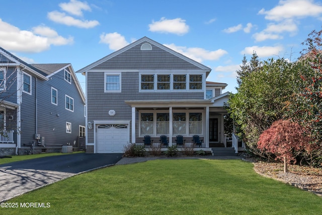 front of property featuring covered porch, cooling unit, a front yard, and a garage