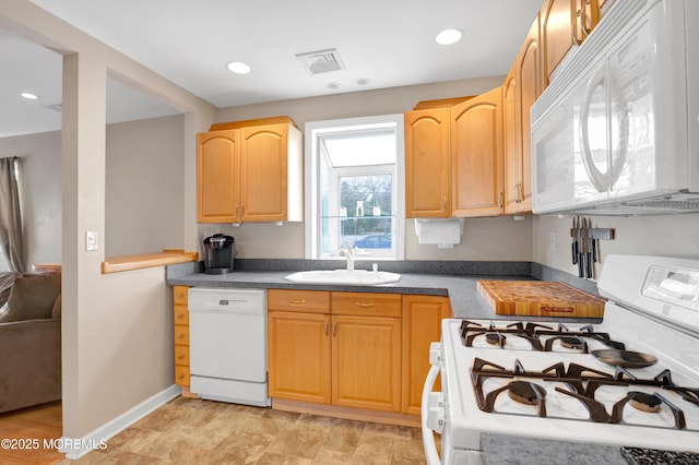 kitchen with light brown cabinets, white appliances, and sink