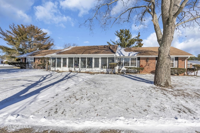 snow covered house featuring a sunroom