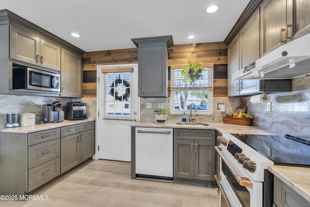 kitchen featuring high end range, white dishwasher, sink, decorative backsplash, and light hardwood / wood-style floors