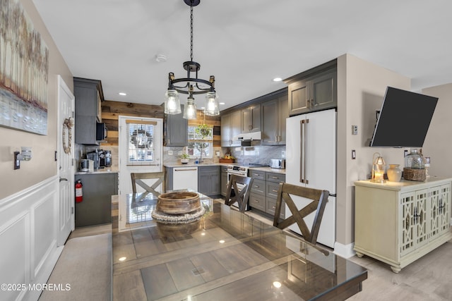 kitchen featuring gray cabinetry, pendant lighting, high end appliances, sink, and decorative backsplash