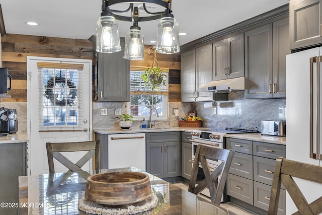 kitchen with gray cabinetry, sink, backsplash, decorative light fixtures, and white appliances