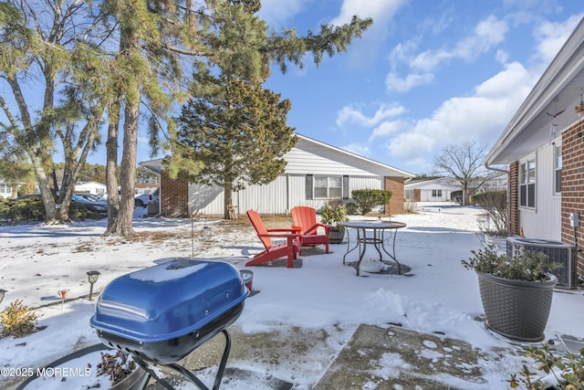 snow covered patio featuring central air condition unit and a grill