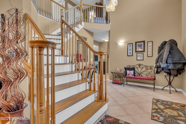 stairway with tile patterned floors, a towering ceiling, and an inviting chandelier