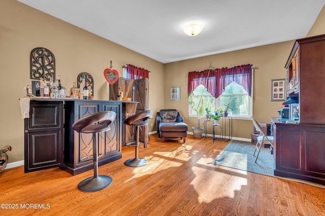 office area with bar and light hardwood / wood-style floors