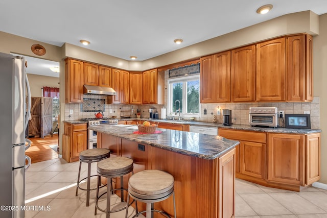 kitchen with a kitchen breakfast bar, a center island, light tile patterned floors, and appliances with stainless steel finishes