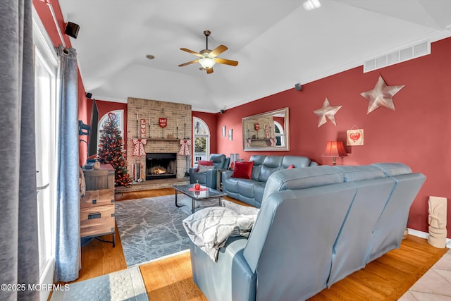 living room featuring a fireplace, ceiling fan, light hardwood / wood-style flooring, and a healthy amount of sunlight