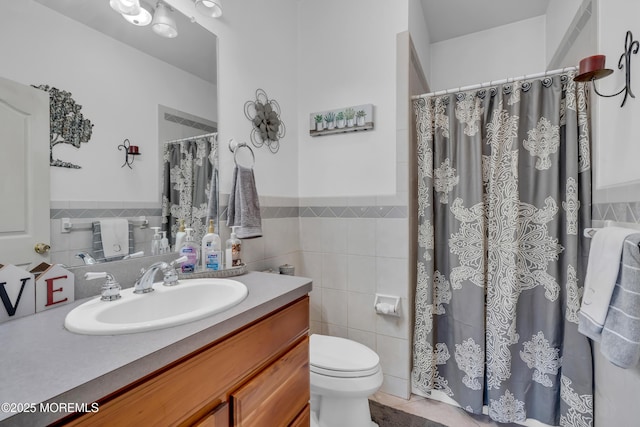 bathroom featuring vanity, toilet, and tile walls