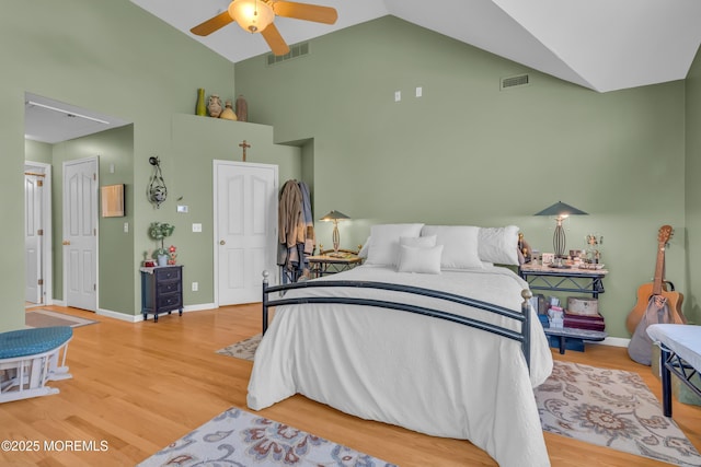 bedroom with a closet, ceiling fan, hardwood / wood-style floors, and high vaulted ceiling