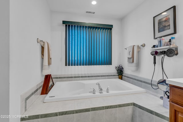 bathroom with vanity and tiled bath