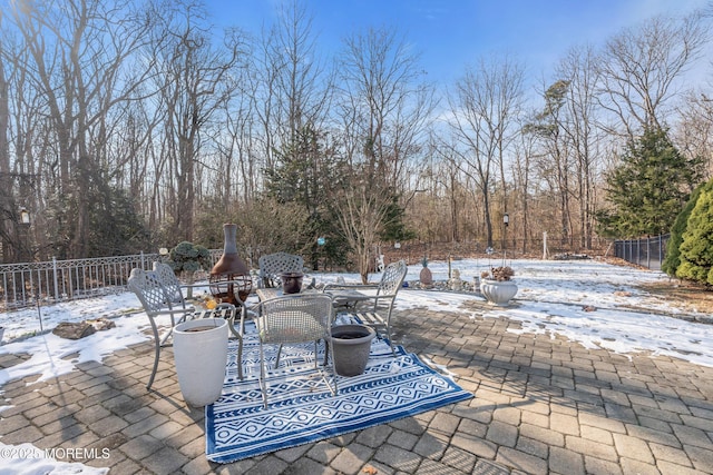 snow covered patio featuring exterior fireplace