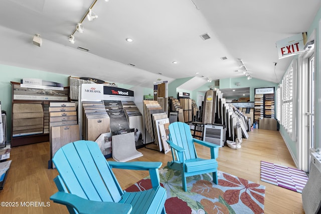 living room with rail lighting, light hardwood / wood-style flooring, and lofted ceiling