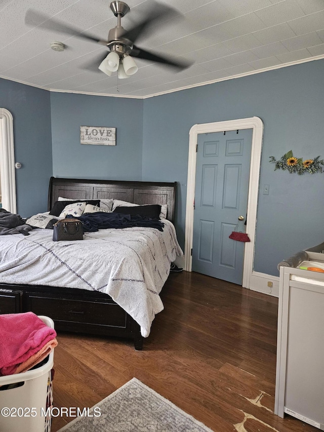 bedroom with ceiling fan, crown molding, and dark wood-type flooring