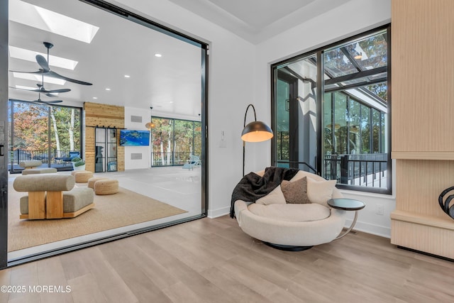 sitting room with a wealth of natural light, a skylight, hardwood / wood-style flooring, and radiator