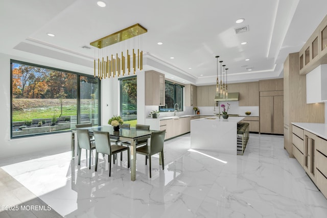 dining space with a tray ceiling, sink, and a chandelier