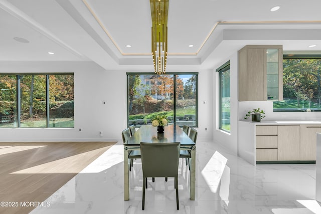 dining room featuring a raised ceiling, plenty of natural light, a notable chandelier, and ornamental molding