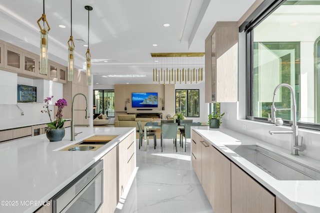 kitchen featuring sink, dishwasher, pendant lighting, and light brown cabinets