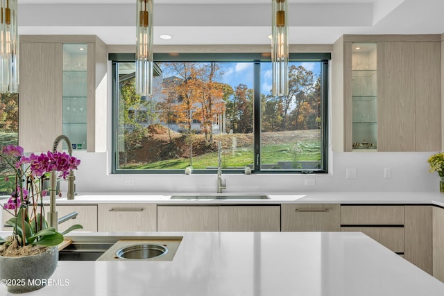 kitchen with light brown cabinetry, pendant lighting, and sink