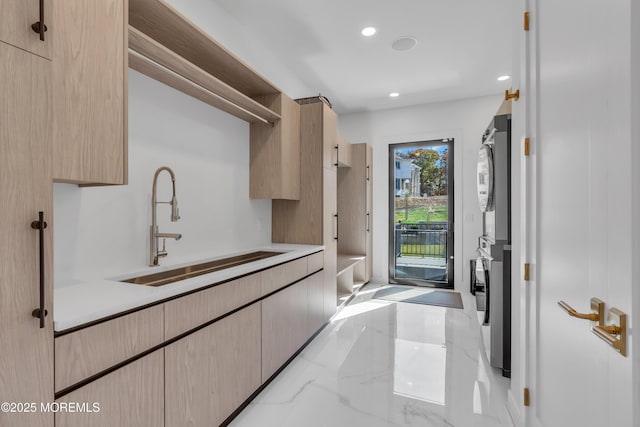 kitchen featuring sink, stacked washer and dryer, and light brown cabinetry