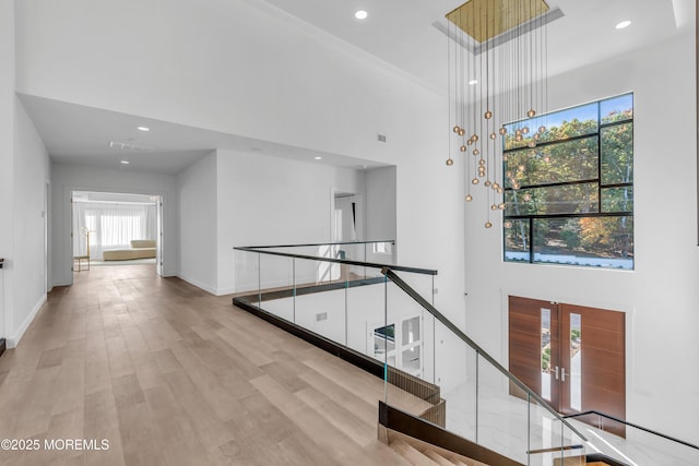 hall with french doors, a high ceiling, and light wood-type flooring