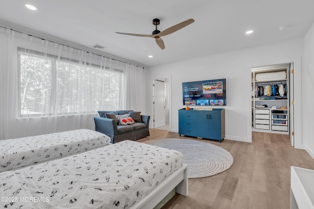 bedroom with a walk in closet, ceiling fan, a closet, and light hardwood / wood-style floors