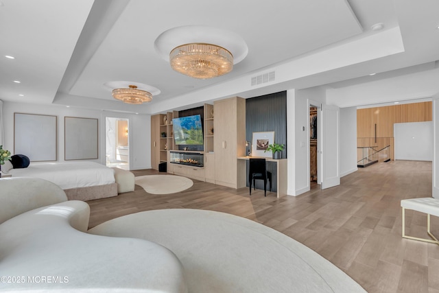 bedroom featuring light hardwood / wood-style floors and a raised ceiling