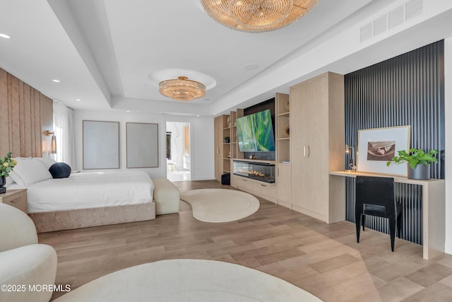 bedroom featuring light hardwood / wood-style flooring and a tray ceiling