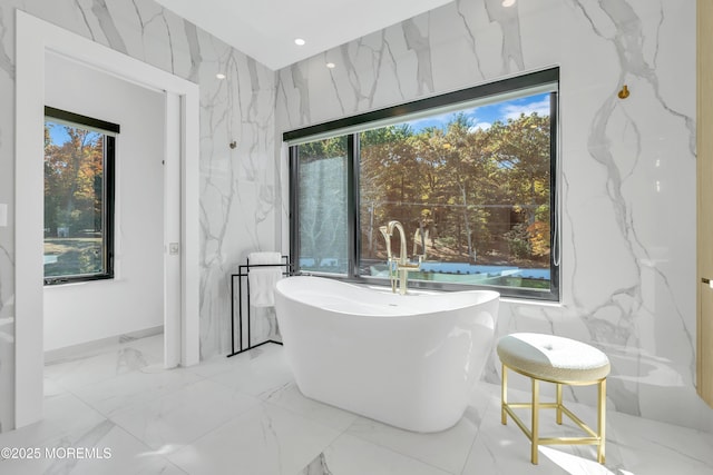 bathroom featuring a bath and tile walls