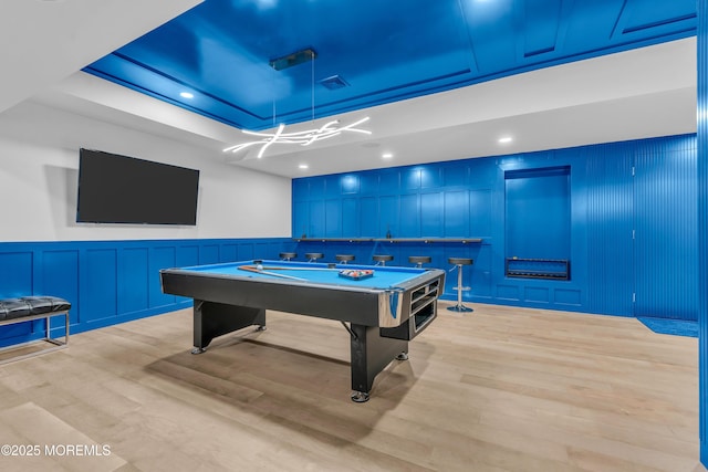 recreation room featuring billiards, a tray ceiling, and light hardwood / wood-style flooring