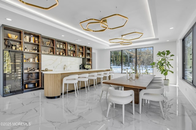 dining space featuring a tray ceiling, plenty of natural light, and wet bar