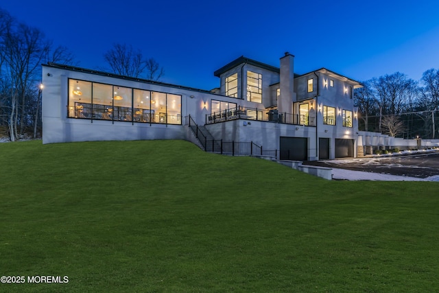 back house at twilight featuring a yard and a garage