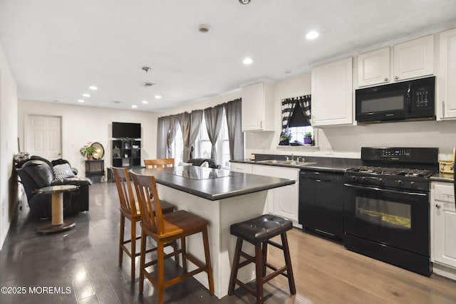 kitchen featuring black appliances, white cabinets, and a breakfast bar area