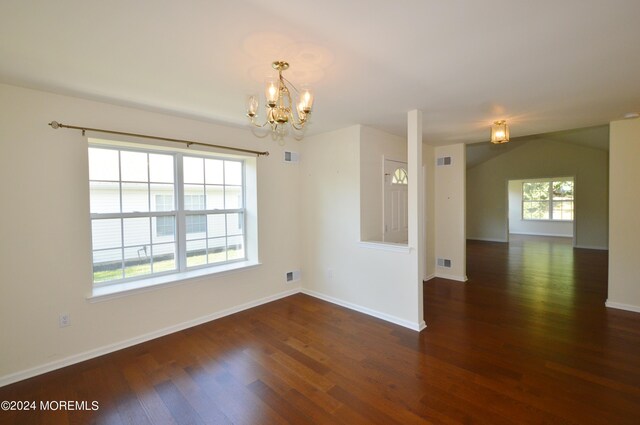 empty room featuring lofted ceiling, dark wood-type flooring, and a chandelier