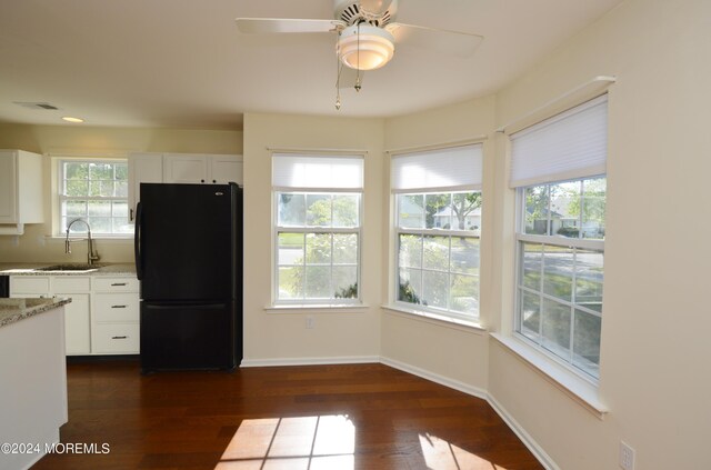 kitchen with white cabinets, black refrigerator, dark hardwood / wood-style flooring, and sink