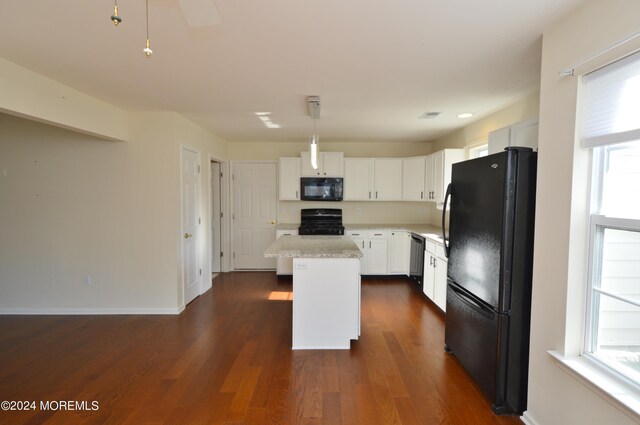 kitchen featuring white cabinetry, a center island, decorative light fixtures, a breakfast bar, and black appliances