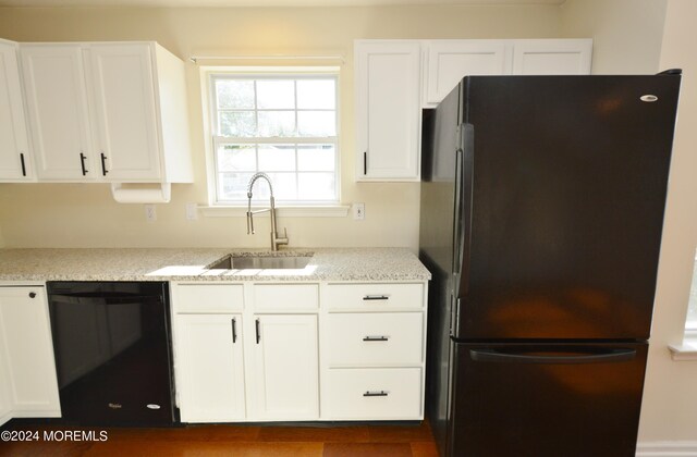 kitchen with black appliances, light stone counters, white cabinets, and sink