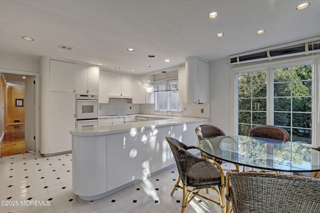 kitchen featuring white cabinetry, kitchen peninsula, and oven