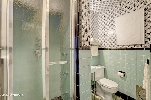 bathroom with tile walls, an enclosed shower, and toilet