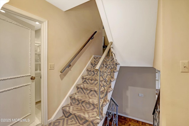 stairway featuring parquet flooring