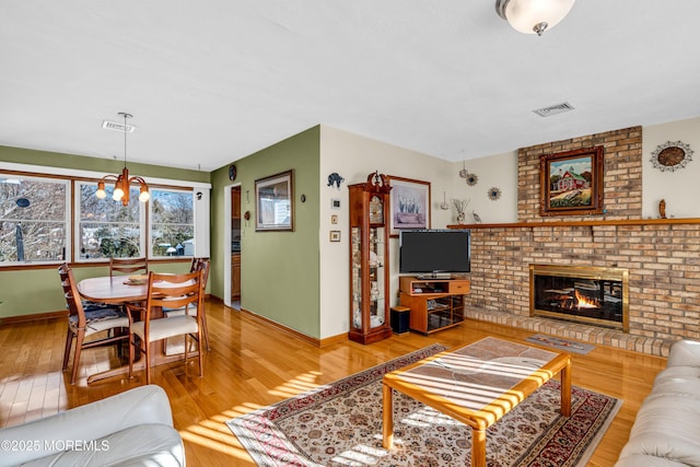 living room featuring a chandelier, a brick fireplace, and hardwood / wood-style floors