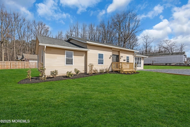 single story home featuring a front lawn and a wooden deck