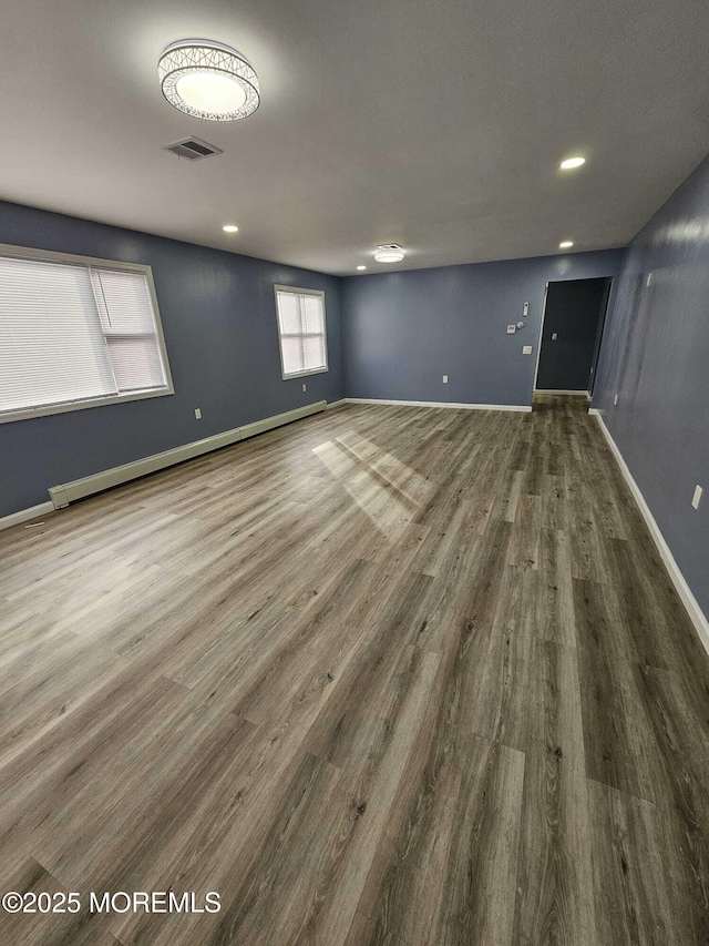 empty room featuring a baseboard heating unit and dark wood-type flooring