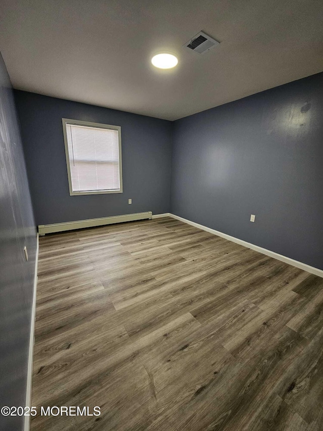 spare room with a baseboard heating unit and hardwood / wood-style floors